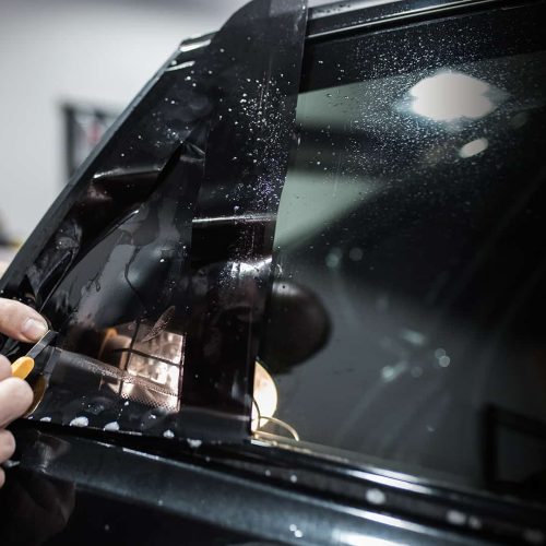 Car tinting - Worker applying tinting foil on car window.